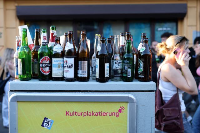 Used beer bottles are seen on an electrical box as pedestrians walk past during the annual leftist May Day demonstration in Berlin's Kreuzberg district on May 1, 2026. (Photo by Odd ANDERSEN / AFP)