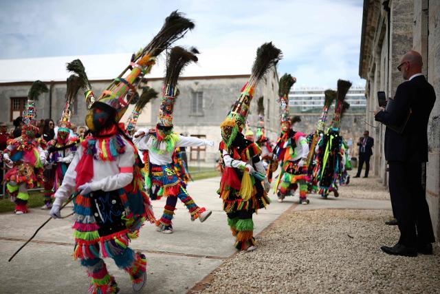 Gombey dancers perform during a cultural welcome for Britain's King Charles III at the Royal Naval Dockyard, Sandys Parish, Bermuda on May 1, 2026. King Charles III is in Bermuda for his first visit to a British Overseas Territory as Sovereign. (Photo by HENRY NICHOLLS / AFP)