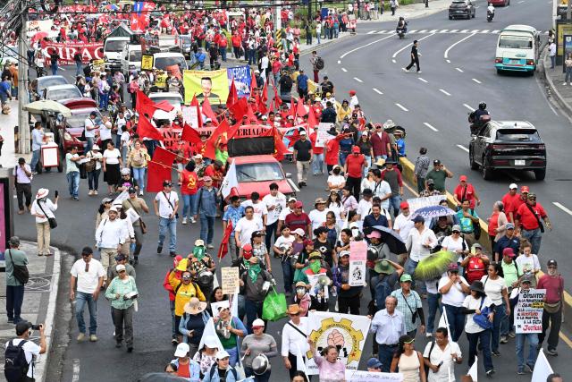 People take part in a march marking International Workers' Day in San Salvador on May 1, 2026. (Photo by MARVIN RECINOS / AFP)
