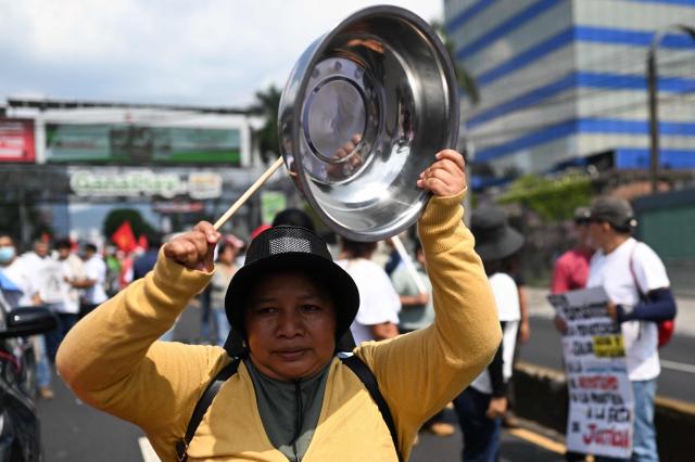 A woman bangs pots and pans as she takes part in a march marking International Workers' Day in San Salvador on May 1, 2026. (Photo by MARVIN RECINOS / AFP)