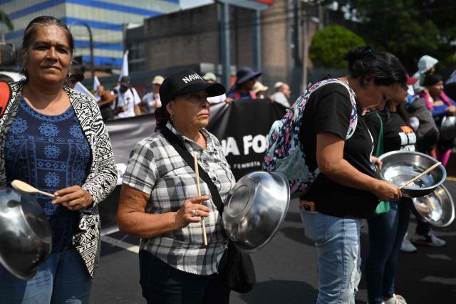 Women bang pots and pans as they take part in a march marking International Workers' Day in San Salvador on May 1, 2026. (Photo by MARVIN RECINOS / AFP)