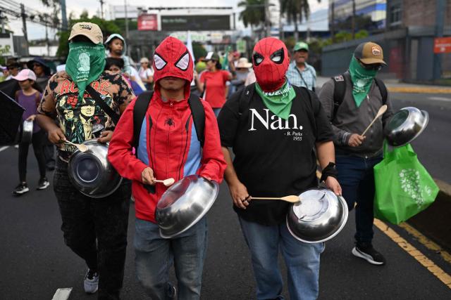 Masked people bang pots and pans as they take part in a march marking International Workers' Day in San Salvador on May 1, 2026. (Photo by MARVIN RECINOS / AFP)