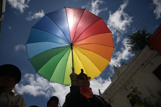 A supporter of Colombia's presidential candidate from the ruling party Pacto Historico, Ivan Cepeda, holds an umbrella bearing pride colours as she takes part in a May Day rally marking International Workers Day in Bogota on May 1, 2026. (Photo by Raul ARBOLEDA / AFP)