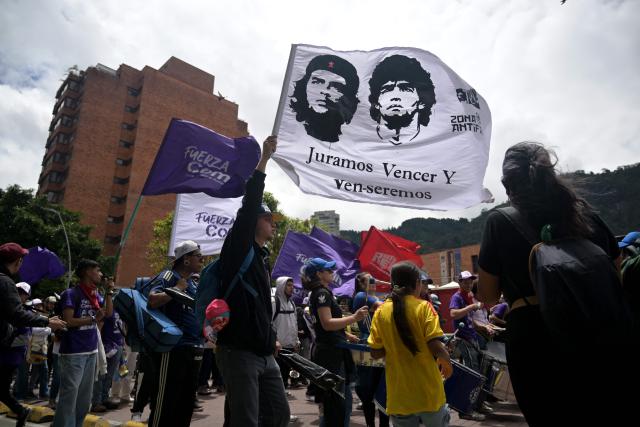A supporter of Colombia's presidential candidate from the ruling party Pacto Historico, Ivan Cepeda, waves a flag with images of Argentine-born Marxist revolutionary Ernesto "Che" Guevara and Argentine football legend Diego Maradona as he takes part in a May Day rally marking International Workers Day in Bogota on May 1, 2026. (Photo by Raul ARBOLEDA / AFP)