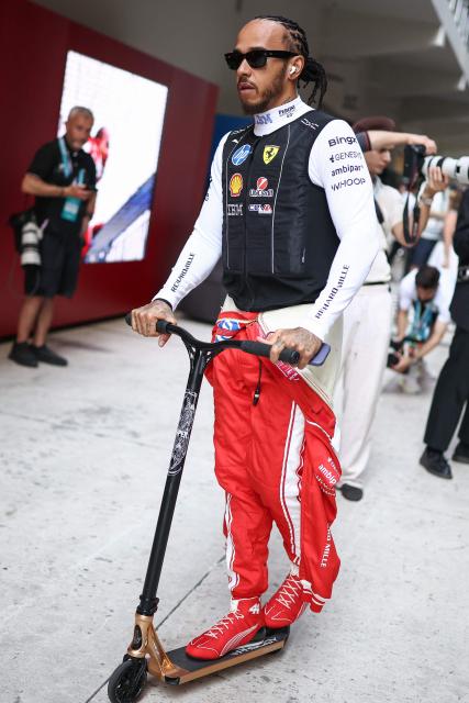 Ferrari's British driver Lewis Hamilton rides a scooter as he makes his way to his garage before the start of Sprint qualifying ahead of the 2026 Miami Formula One Grand Prix at Miami International Autodrome in Miami Gardens, Florida, on May 1, 2026. (Photo by CHARLY TRIBALLEAU / AFP)