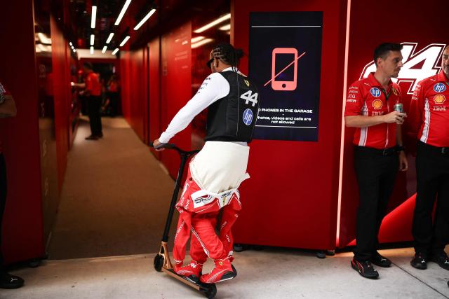 Ferrari's British driver Lewis Hamilton rides a scooter as he makes his way to his garage before the start of Sprint qualifying ahead of the 2026 Miami Formula One Grand Prix at Miami International Autodrome in Miami Gardens, Florida, on May 1, 2026. (Photo by CHARLY TRIBALLEAU / AFP)