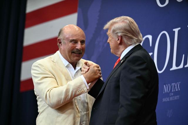 US President Donald Trump shakes hands with US TV personality Phil McGraw, better known as Dr. Phil, after giving a speech about taxes and Social Security in The Villages, Florida, on May 1, 2026. (Photo by Jim WATSON / AFP)