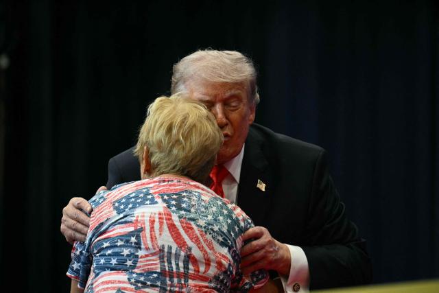 US President Donald Trump kisses a supporter during an event where he spoke about taxes and Social Security in The Villages, Florida, on May 1, 2026. (Photo by Jim WATSON / AFP)