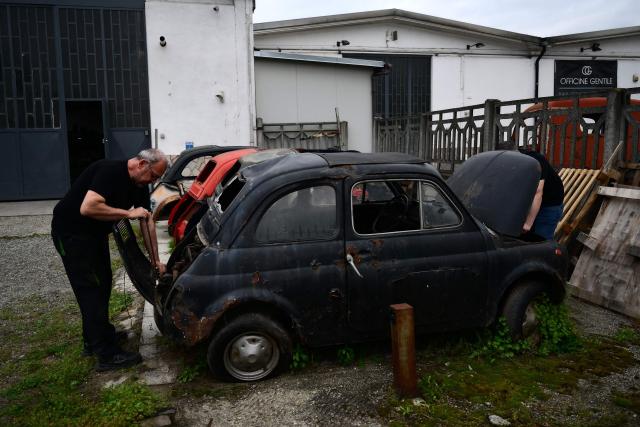 Workers operate on an old Fiat 500 model that will be transformed into an electric 500 Jolly Lido model at the Officine Gentile garage in Turin on April 30, 2026. In the Officine Gentile workshop in Turin -- the historic home of Italian carmaker Fiat -- vintage 500 models are getting a makeover with electric engines. The original Fiat 500 became a design icon and some 4.2 million models were made. The retrofitted cars sell for around 40-50,000 euros with convertibles for up to 80,000 euros. (Photo by MARCO BERTORELLO / AFP)