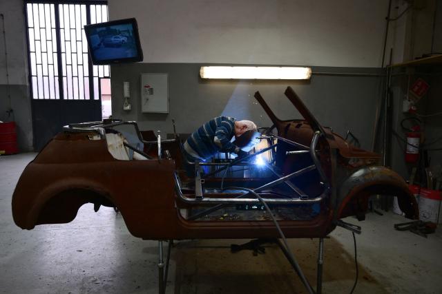 A worker welds the frame of an old Fiat 500 model that will be transformed into an electric 500 Jolly Lido model at the Officine Gentile garage in Turin on April 30, 2026. In the Officine Gentile workshop in Turin -- the historic home of Italian carmaker Fiat -- vintage 500 models are getting a makeover with electric engines. The original Fiat 500 became a design icon and some 4.2 million models were made. The retrofitted cars sell for around 40-50,000 euros with convertibles for up to 80,000 euros. (Photo by MARCO BERTORELLO / AFP)