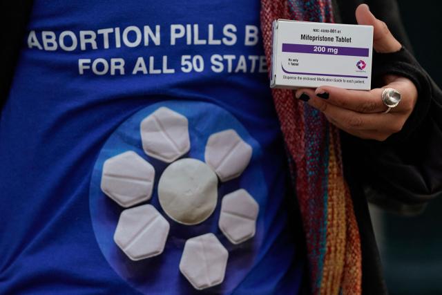 (FILES) A pro-abortion rights activist holds a box of mifepristone during a rally in front of the US Supreme Court on March 26, 2024, in Washington, DC. A US appeals court on Friday temporarily halted mail delivery ofmifepristone, the medication used in the majority of abortions in the United States. (Photo by Drew ANGERER / AFP)