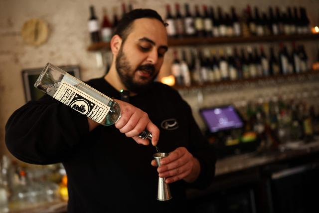 A bartender prepares a cocktail using the traditional Iranian spirit "Aragh Sagi" produced in Yonkers, at a restaurant in the Brooklyn borough of New York City, on April 28, 2026. Three Iranian men pressed rehydrated raisins at an artisan distillery just outside New York, thousands of miles from their war-struck homeland. They were carefully producing aragh sagi, a traditional spirit banned by the clerical authorities along with all alcohol following the 1979 Islamic revolution. Despite its outlaw moonshine status, the drink is still made clandestinely and consumed inside Iran. (Photo by CHARLY TRIBALLEAU / AFP)