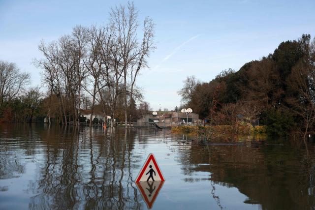 (FILES) A road sign is partially submerged in a flooded street following heavy rain causing the flooding of the Charente river in Chaniers, southwestern France on February 20, 2026. (Photo by ROMAIN PERROCHEAU / AFP)