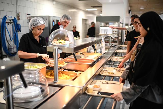 (FILES) CROUS employees serve dishes to students queueing up prior to a meal at a CROUS (Centre Regional des Oeuvres Universitaires et Scolaires) university restaurant at the Bordeaux University in Talence, south-western France, on April 24, 2026. From May 4, 2026, all students, regardless of their income, will be able to eat in university canteens for just one euro – a measure called for by student organisations and included in the 2026 budget as a concession by the government to Socialist MPs.
The one-euro meal in canteens run by the Regional Centres for University and School Services (Crous) already exists for students on grants and those in financial difficulty. Until now, other students have been paying 3.30 euros – they had temporarily benefited from one-euro meals during the Covid pandemic. (Photo by Christophe ARCHAMBAULT / AFP)