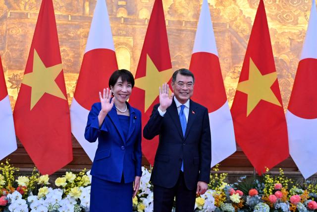 Vietnam's Prime Minister Le Minh Hung (R) and Japan's Prime Minister Sanae Takaichi (L) wave at the Government Office in Hanoi on May 2, 2026. (Photo by Nhac NGUYEN / POOL / AFP)