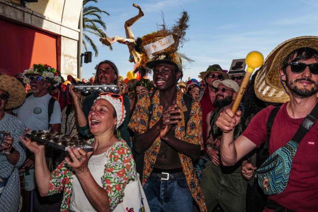 Revelers participate at the traditional "Santa Capelina" festival in Nice, south-eastern France, on May 1, 2026. Revelers gather on May 1 in Nice to celebrate the annual Santa Capelina, parading in hand-made hats and sharing a fish soup cooked on site, with each participant contributing their own fish. A Santa figure, built collectively from branches and flowers with a papier-mâché head, is carried in a procession to the beach before casting it into the sea. (Photo by Valery HACHE / AFP)