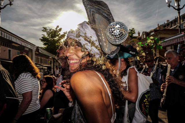 Revelers in makeshift hats participate at the traditional "Santa Capelina" festival in Nice, south-eastern France, on May 1, 2026. Revelers gather on May 1 in Nice to celebrate the annual Santa Capelina, parading in hand-made hats and sharing a fish soup cooked on site, with each participant contributing their own fish. A Santa figure, built collectively from branches and flowers with a papier-mâché head, is carried in a procession to the beach before casting it into the sea. (Photo by Valery HACHE / AFP)