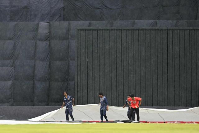 Groundsmen cover the pitch as rain halts play during the third T20 cricket match between Bangladesh and New Zealand at the Sher-e-Bangla National Stadium in Mirpur on May 2, 2026. (Photo by Munir UZ ZAMAN / AFP)