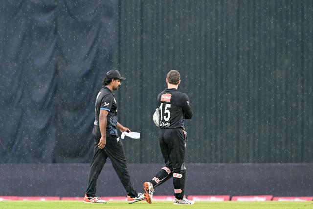 New Zealand's Ish Sodhi (L) and wicketkeeper Dane Cleaver walk back to the pavilion as rain halts play during the third T20 cricket match between Bangladesh and New Zealand at the Sher-e-Bangla National Stadium in Mirpur on May 2, 2026. (Photo by Munir UZ ZAMAN / AFP)