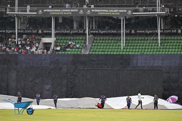 Groundsmen cover the pitch as rain halts play during the third T20 cricket match between Bangladesh and New Zealand at the Sher-e-Bangla National Stadium in Mirpur on May 2, 2026. (Photo by Munir UZ ZAMAN / AFP)