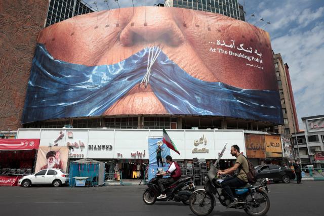 Motorists ride past an anti-US billboard referring to President Donald Trump and the Strait of Hormuz, installed on a building at the Valiasr Square in Tehran on May 2, 2026. A senior Iranian military officer said on May 2 that renewed fighting between the US and Iran was "likely", hours after President Donald Trump said he was "not satisfied" with a new Iranian negotiating proposal. (Photo by AFP) / 