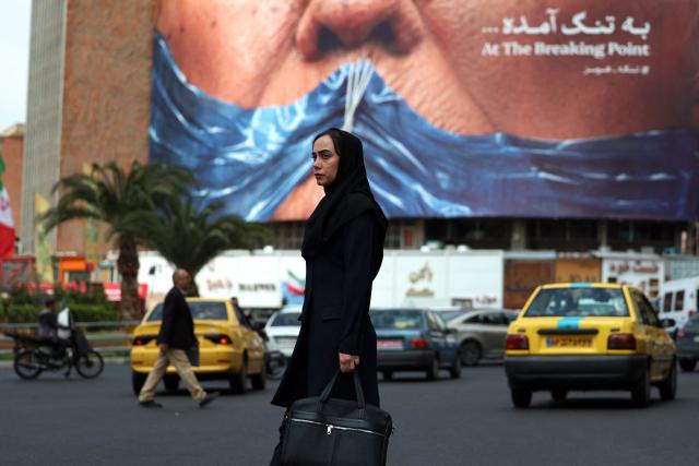 A woman walks past an anti-US billboard referring to President Donald Trump and the Strait of Hormuz, installed on a building at the Valiasr Square in Tehran on May 2, 2026. A senior Iranian military officer said on May 2 that renewed fighting between the US and Iran was "likely", hours after President Donald Trump said he was "not satisfied" with a new Iranian negotiating proposal. (Photo by AFP) / 