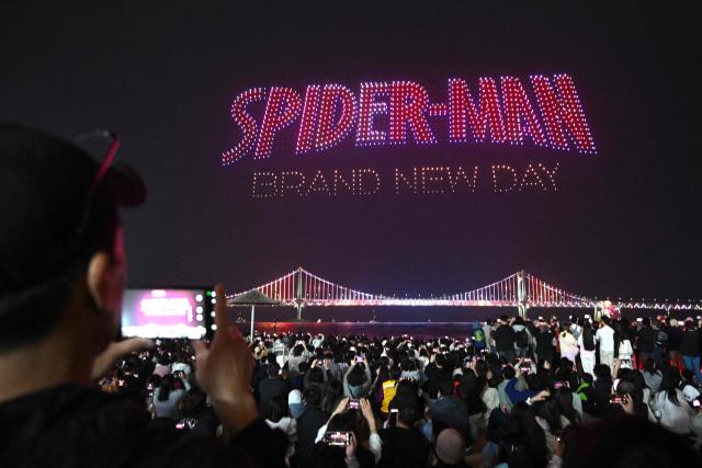 A swarm of 1,500 drones forms patterns in the night sky above Gwangan Bridge during a drone light show to promote the movie "Spider-Man: Brand New Day" at Gwangalli Beach in Busan on May 2, 2026. (Photo by Jung Yeon-je / AFP)