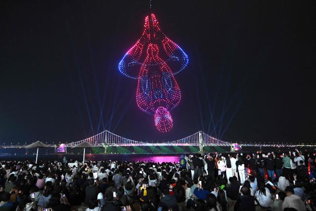 A swarm of 1,500 drones forms the shape of Spider-Man in the night sky above Gwangan Bridge during a drone light show to promote the movie "Spider-Man: Brand New Day" at Gwangalli Beach in Busan on May 2, 2026. (Photo by Jung Yeon-je / AFP)