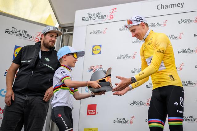 UAE Team Emirates-XRG's Slovenian rider Tadej Pogacar (R) wearing the overall leader's yellow jersey receives a trophy during the podium ceremony after winning the of the fourth stage of the Tour of Romandie UCI cycling World tour, 149.6 km from Broc and to Charmey, in Charmey, Switzerland, on May, 2, 2026. (Photo by Fabrice COFFRINI / AFP)