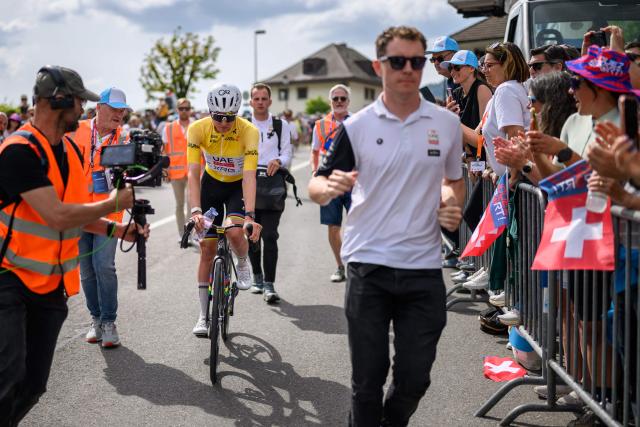 UAE Team Emirates-XRG's Slovenian rider Tadej Pogacar wearing the overall leader's yellow jersey is escorted to the podium after winning the fourth stage of the Tour of Romandie UCI cycling World tour, 149.6 km from Broc and to Charmey, in Charmey, Switzerland, on May, 2, 2026. (Photo by Fabrice COFFRINI / AFP)