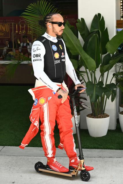 Ferrari's British driver Lewis Hamilton rides a scooter as he makes his way from the paddock to the garage ahead of the 2026 Miami Formula One Sprint at Miami International Autodrome in Miami Gardens, Florida, on May 2, 2026. (Photo by CHANDAN KHANNA / AFP)