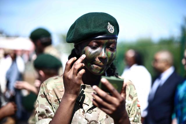 A member of Bermuda's Coast Guard paints her face with camouflage paint during Britain's King Charles III's visit to the Great Bay Coast Guard Station in St. David's, Bermuda, on May 2, 2026. King Charles III is in Bermuda for his first visit to a British Overseas Territory as Sovereign. (Photo by Henry NICHOLLS / AFP)