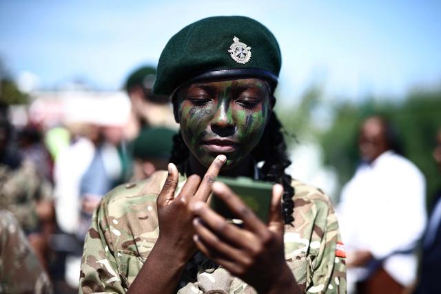 A member of Bermuda's Coast Guard paints her face with camouflage paint during Britain's King Charles III's visit to the Great Bay Coast Guard Station in St. David's, Bermuda, on May 2, 2026. King Charles III is in Bermuda for his first visit to a British Overseas Territory as Sovereign. (Photo by Henry NICHOLLS / AFP)