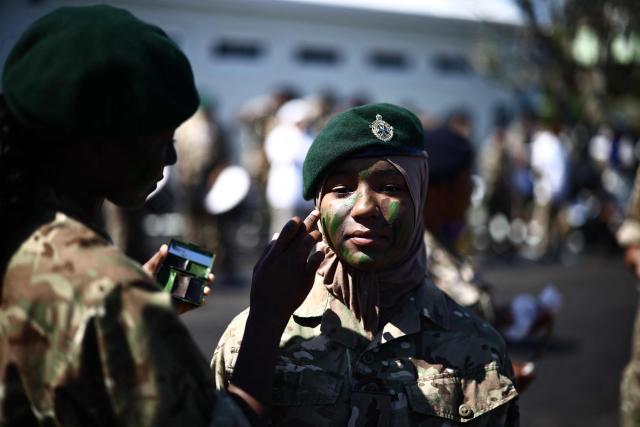 Members of Bermuda's Coast Guard paint their faces with camouflage paint during Britain's King Charles III's visit to the Great Bay Coast Guard Station in St. David's, Bermuda, on May 2, 2026. King Charles III is in Bermuda for his first visit to a British Overseas Territory as Sovereign. (Photo by Henry NICHOLLS / AFP)