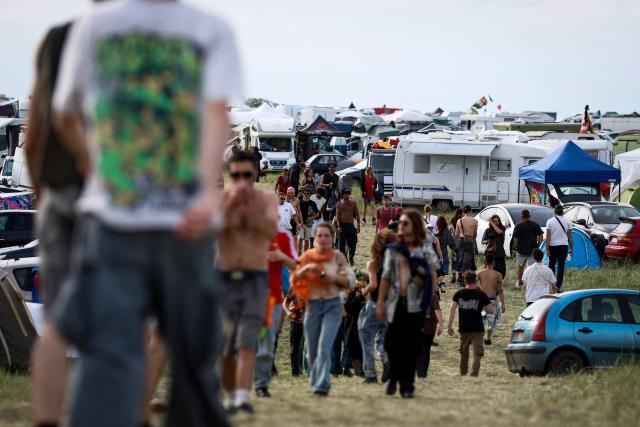 Revellers stroll at the site of a "teknival" rave party at a military site in Cornusse, near Bourges, central France on May 2, 2026. Around 20,000 partygoers gathered on May 1 for an illegal rave at a military site in France, defying warnings about the risk of unexploded ordnance and possible blasts. The rave near the town of Bourges in central France kicked off on May 1 and organisers expect as many as 30,000 people from France and neighbouring countries to arrive at the peak of the event this weekend. (Photo by Kenzo TRIBOUILLARD / AFP)