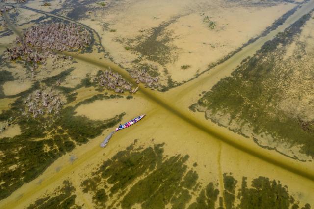 An aerial photograph shows a fishing boat moving in the al-Chibayish Marches following recent rains, near the town of Al-Chibayish close to the Euphrates River in Dhi Qar governorate, southern Iraq on May 2, 2026. The Al-Chibayish Marshes are part of the larger Mesopotamian Marshes system between the Tigris and Euphrates rivers, and the largest wetlands in Southwest Asia. They are important wetlands for migratory birds, endemic birds, fish, and buffalo breeding and also home to the March Arabs. (Photo by Assad NIYAZI / AFP)