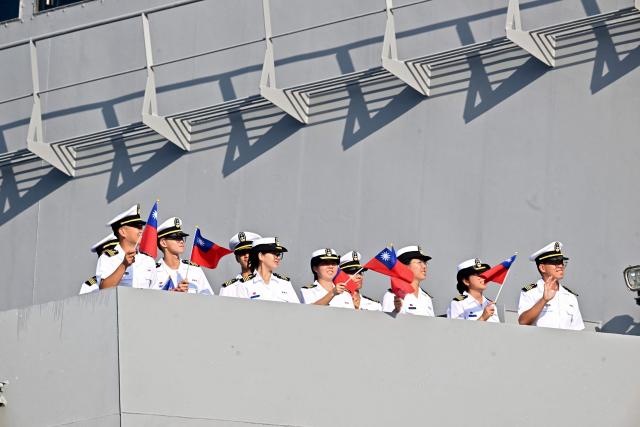 Members of the Taiwanese navy flutter Taiwanese flags onboard one of three Taiwanese Navy warships after their arrival at Puerto Quetzal, Guatemala on May 2, 2026, as part of a naval squadron. The three vessels -- described as being on a training mission -- powered into Puerto Quetzal, a port town on Guatemala's Pacific coast, in a visit "to strengthen the ties of friendship," Guatemalan officials and Taiwanese diplomats said. (Photo by Johan ORDONEZ / AFP)