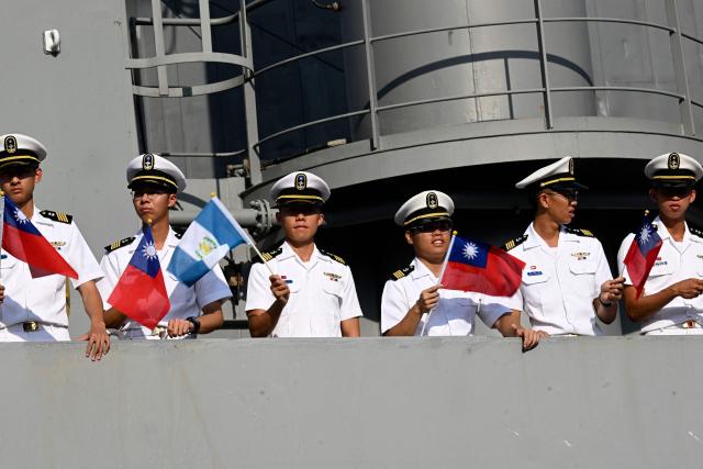 Members of the Taiwanese navy flutter Taiwanese and Guatemalan flags onboard one of three Taiwanese Navy warships after their arrival at Puerto Quetzal, Guatemala on May 2, 2026, as part of a naval squadron. The three vessels -- described as being on a training mission -- powered into Puerto Quetzal, a port town on Guatemala's Pacific coast, in a visit "to strengthen the ties of friendship," Guatemalan officials and Taiwanese diplomats said. (Photo by Johan ORDONEZ / AFP)