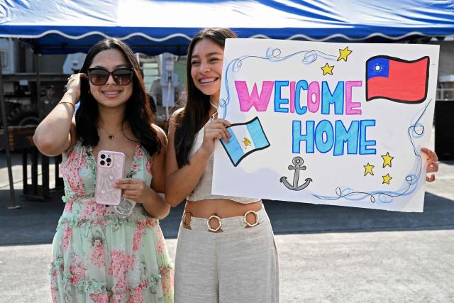 Women wait with a sign after three Taiwanese Navy warships arrived at Puerto Quetzal, Guatemala on May 2, 2026, as part of a naval squadron. The three vessels -- described as being on a training mission -- powered into Puerto Quetzal, a port town on Guatemala's Pacific coast, in a visit "to strengthen the ties of friendship," Guatemalan officials and Taiwanese diplomats said. (Photo by Johan ORDONEZ / AFP)