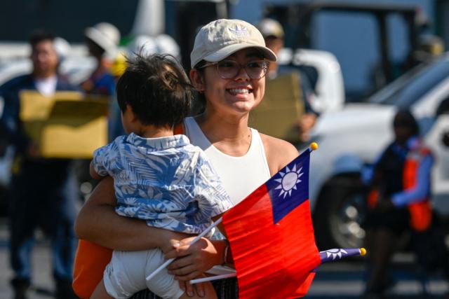 A woman holds a Taiwanese flag after three Taiwanese Navy warships arrived at Puerto Quetzal, Guatemala on May 2, 2026, as part of a naval squadron. The three vessels -- described as being on a training mission -- powered into Puerto Quetzal, a port town on Guatemala's Pacific coast, in a visit "to strengthen the ties of friendship," Guatemalan officials and Taiwanese diplomats said. (Photo by Johan ORDONEZ / AFP)