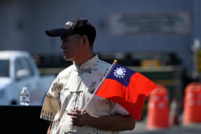 A man holds a Taiwanese flag after three Taiwanese Navy warships arrived at Puerto Quetzal, Guatemala on May 2, 2026, as part of a naval squadron. The three vessels -- described as being on a training mission -- powered into Puerto Quetzal, a port town on Guatemala's Pacific coast, in a visit "to strengthen the ties of friendship," Guatemalan officials and Taiwanese diplomats said. (Photo by Johan ORDONEZ / AFP)