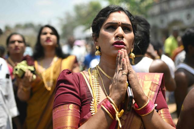 This photograph taken on April 29, 2026 shows Thilothama, a member of the transgender community offering prayers to a chariot procession of Hindu warrior god Aravan during the annual Koovagam transgender festival at the Koothandavar temple in Tamil Nadu's Kallakurichi district. For a few fleeting days each year, at the heart of the Koothandavar Temple where ostracised transgender community members from across India come to honour the Hindu deity Aravan, a tradition rooted in millennia-old Hindu texts -- and to enjoy a brief oasis of freedom, for the past 10 years Thilothama has returned to Koovagam, where a beauty pageant and singing contests are held alongside religious rituals. (Photo by R.Satish BABU / AFP)