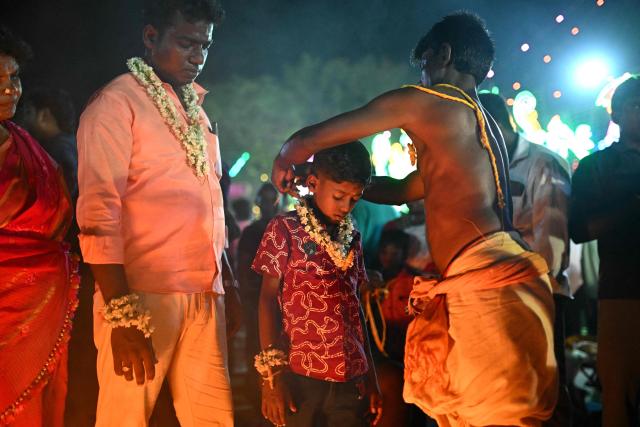 This photograph taken on April 28, 2026 shows a boy getting "thali", a sacred thread tied to his neck symbolising marriage to Hindu warrior god Aravan during the annual Koovagam transgender festival at the Koothandavar temple in Tamil Nadu's Kallakurichi district. For a few fleeting days each year, at the heart of the Koothandavar Temple where ostracised transgender community members from across India come to honour the Hindu deity Aravan, a tradition rooted in millennia-old Hindu texts -- and to enjoy a brief oasis of freedom. (Photo by R.Satish BABU / AFP)