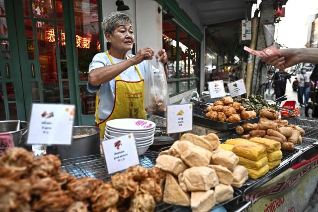 This photo taken on April 29, 2026 shows street food vendor Thitisakulthip Sang-uamsap selling fried vegetarian snacks in Chinatown in Bangkok. Across Bangkok, aromas of garlic, chilli and grilled meat drift from roadside stalls and carts, but tighter controls on vendors threaten livelihoods and the street food culture that defines the Thai capital. (Photo by Lillian SUWANRUMPHA / AFP) / To go with AFP story Thailand-Bangkok-food-culture-economy,FOCUS by Montira Rungjirajittranon