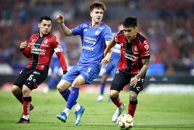 Atlas' forward #25 Jorge Rodriguez (R) and Cruz Azul's Argentine midfielder #08 Agustin Palavecino (C) fight for the ball during the Mexican League Clausura Tournament quarterfinal first leg football match between Atlas and Cruz Azul at the Jalisco stadium in Guadalajara, Jalisco state, Mexico on May 2, 2026. (Photo by Ulises RUIZ / AFP)