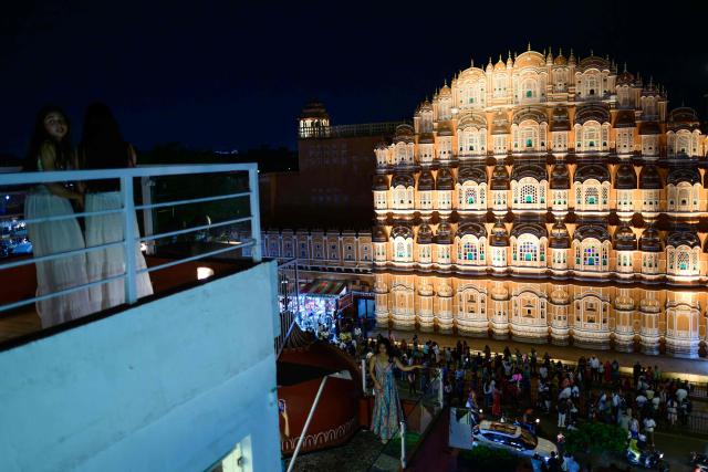 Tourists take a selfie against the backdrop of landmark Hawa Mahal or "Palace of Winds”, at a rooftop cafe in Jaipur on May 2, 2026. (Photo by Manan VATSYAYANA / AFP)