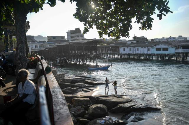 Women (R) take photos along the coast during sunset in Hua Hin on May 1, 2026. (Photo by Amaury PAUL / AFP)