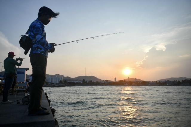 A man fishes during sunset in Hua Hin on May 1, 2026. (Photo by Amaury PAUL / AFP)