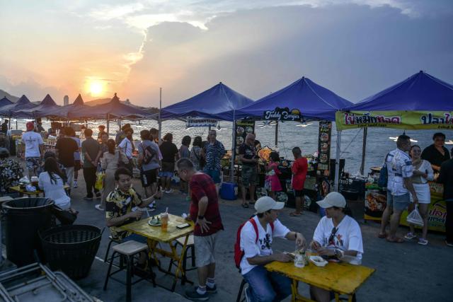 People buy food and sit at a market during sunset in Hua Hin on May 1, 2026. (Photo by Amaury PAUL / AFP)