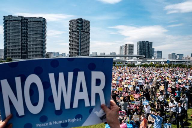 People hold placards reading “No war” and “Stop constitutional revision, military expansion” during the Grand Constitution Rally 2026 to mark Constitution Memorial Day in Tokyo on May 3, 2026. (Photo by Philip FONG / AFP)